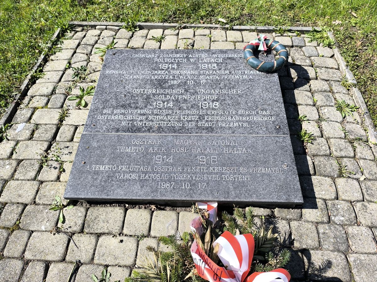 Kétnyelvű emléktábla koszorúval a temetőben